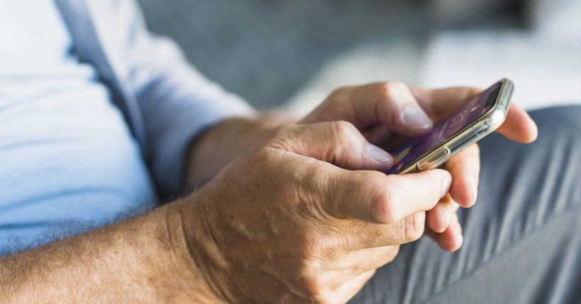 Persona mayor usando un móvil con ayuda
